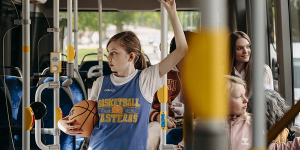 Resenärer på buss, bland annat ung tjej med basketboll